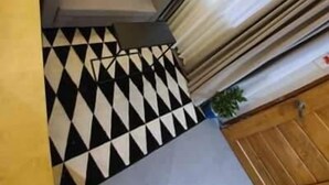 A compact living space with a sofa, a small table, a potted plant, and a patterned floor. - Radlett Residences (Tuguegarao)