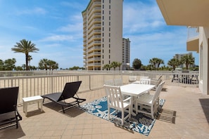 A rooftop patio with outdoor furniture, a view of a tall building, and palm trees.