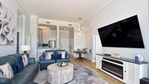 A modern living room with a sofa, ottoman, and a flat-screen TV mounted on the wall. - 2 Bedroom Beach Front Condo (Destin)