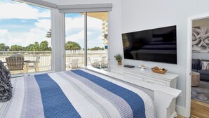 A bedroom with a large bed, a TV, and a balcony with outdoor furniture. - 2 Bedroom Beach Front Condo (Destin)
