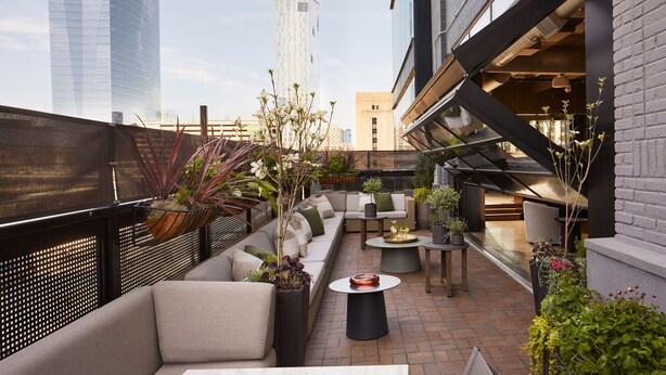 A rooftop patio with outdoor seating, potted plants, and a view of city buildings. - Fitler Club (Philadelphia)