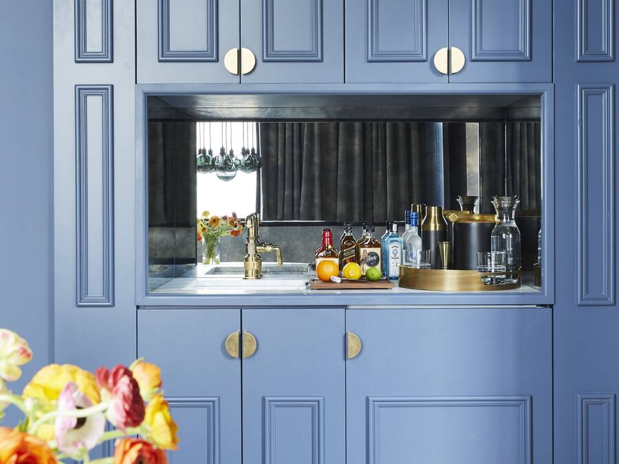 A bar area with a blue cabinet, a sink, and various bottles and glasses.