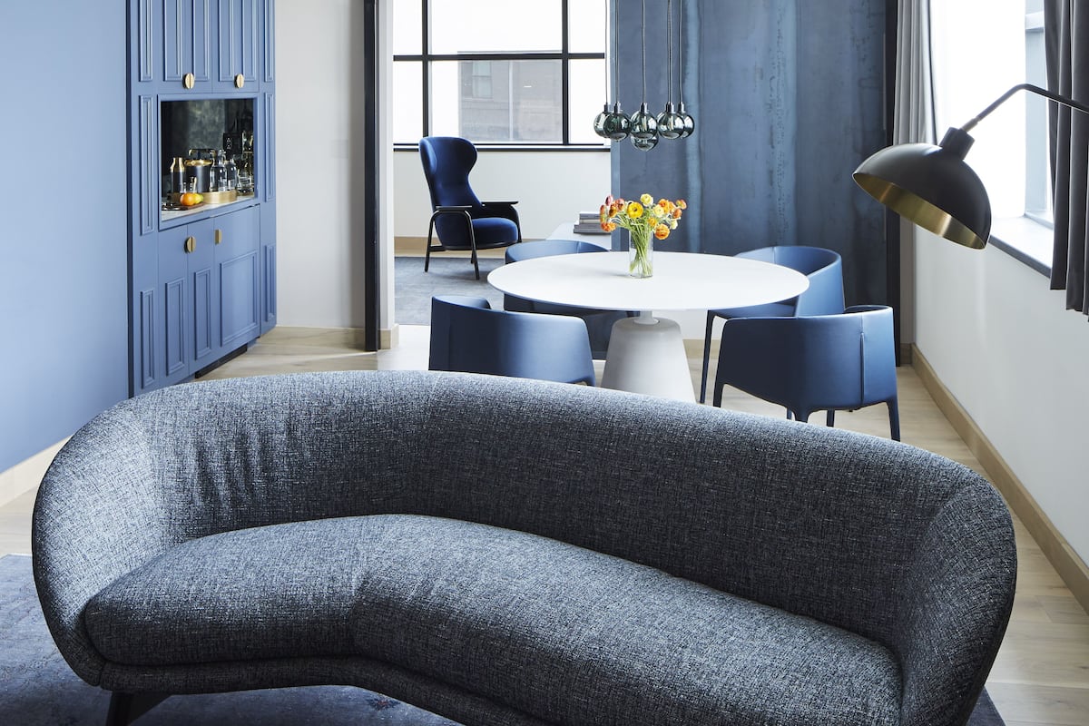 Un espace repas moderne avec une table ronde, des chaises bleues et un canapé bleu.