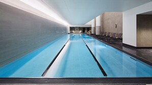 A long indoor swimming pool with clear lanes, lounge chairs, and a modern interior design. - Fitler Club (Philadelphia)