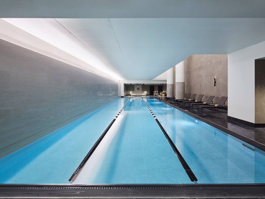 Uma piscina interior extensa com pistas bem definidas, espreguiçadeiras e um design de interiores moderno.