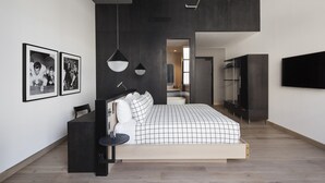 A modern bedroom with a large bed, a desk, and a TV mounted on the wall. - Fitler Club (Philadelphia)