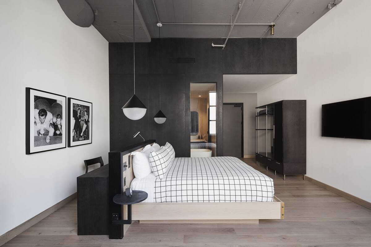 Une chambre moderne avec un grand lit, un bureau et un téléviseur fixé au mur.