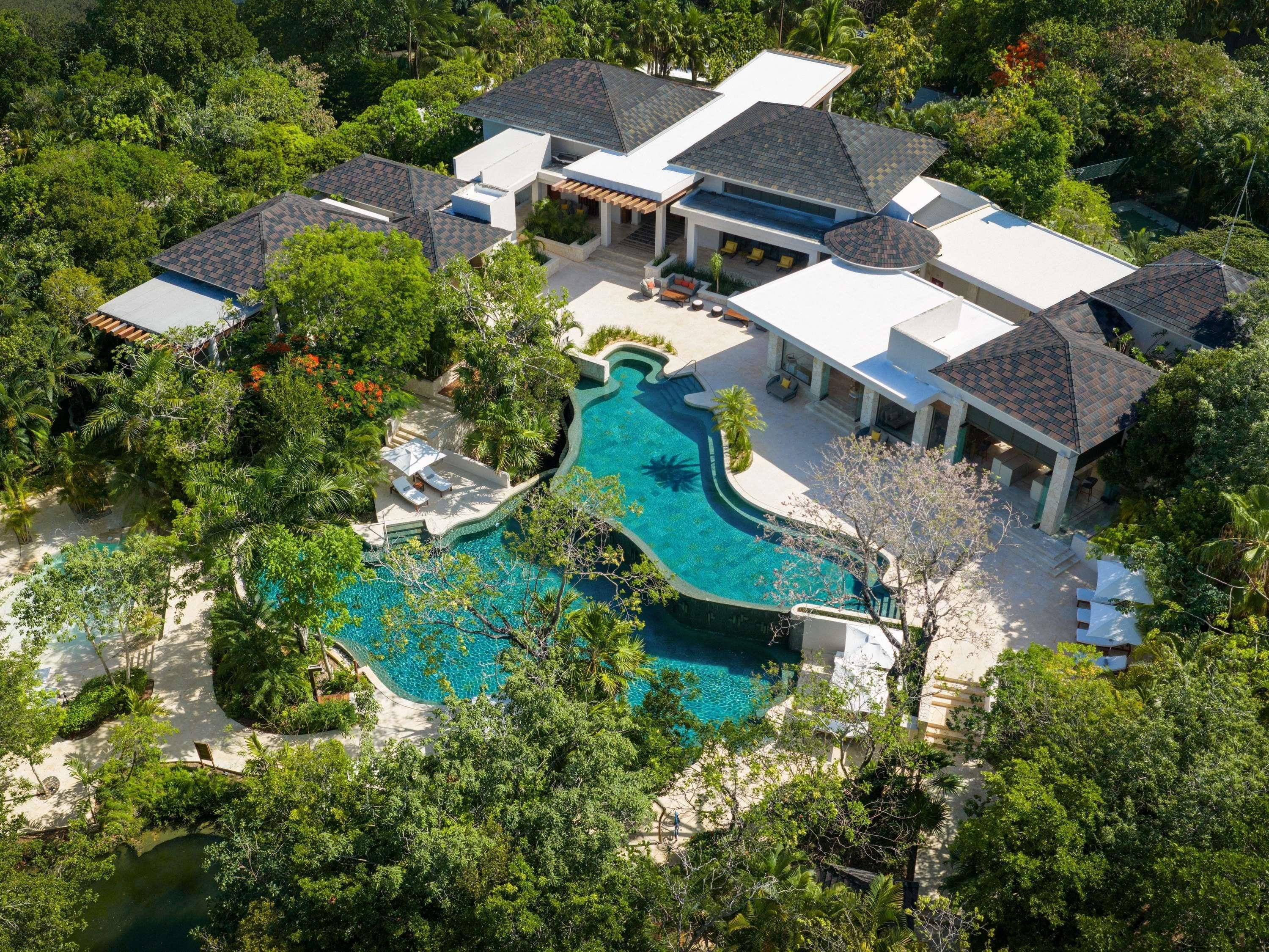 A large house with a swimming pool surrounded by lush greenery.