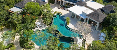 A large house with a swimming pool surrounded by lush greenery.