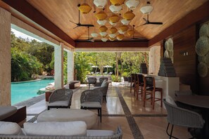 A covered outdoor area with a pool, wicker furniture, and ceiling fans. - Fairmont Heritage Place Mayakoba (Playa del Carmen)