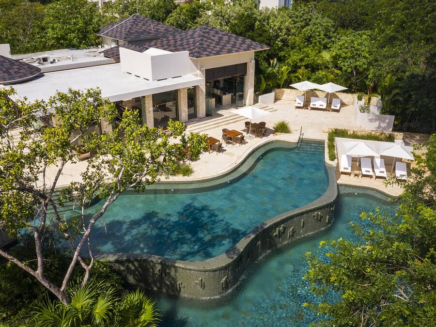 A luxurious property with a large swimming pool, outdoor seating, and a well-maintained garden.