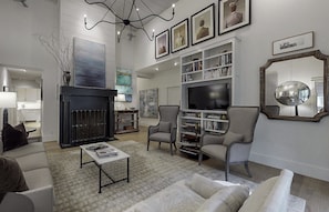 A modern living room with a fireplace, comfortable seating, a television, and a bookshelf.