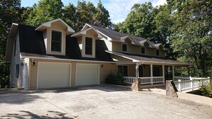 Une maison à deux étages avec un porche couvert et deux garages attenants.