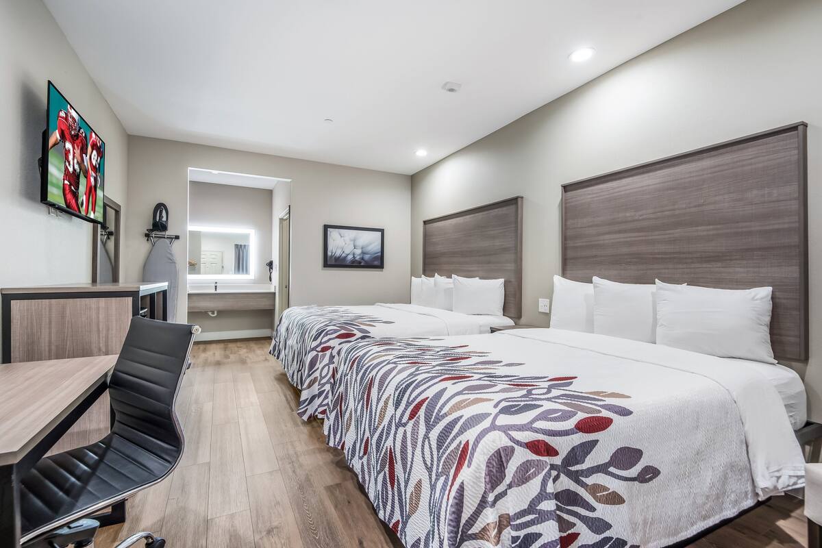 A hotel room with a bed, a desk, a chair, a television, and a picture on the wall.