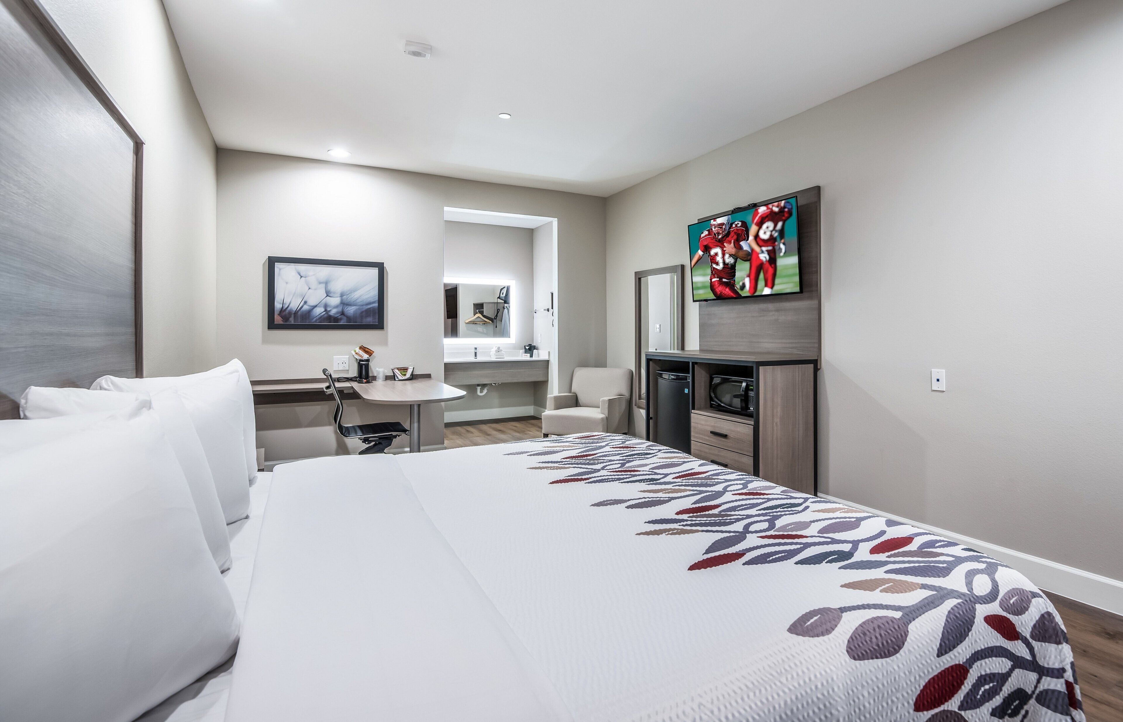 Ein Hotelzimmer mit einem großen Bett, einem Schreibtisch, einem Fernseher und einem Badezimmer.