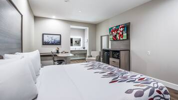 Ein Hotelzimmer mit einem großen Bett, einem Schreibtisch, einem Fernseher und einem Badezimmer.