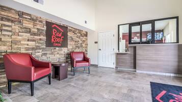 A reception area with a stone wall, two red chairs, a reception desk, and a door labeled 'STAFF ONLY'.