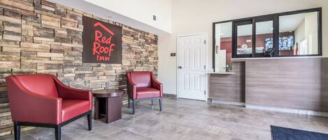 A reception area with a stone wall, two red chairs, a reception desk, and a door labeled 'STAFF ONLY'.