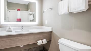 A modern bathroom with a large mirror, a sink, a toilet, and a towel rack.