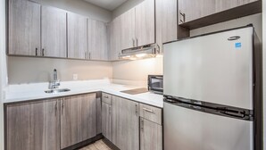 A modern kitchen with light wood cabinetry, stainless steel appliances, and a white countertop. - Red Roof Inn Baytown (Baytown)