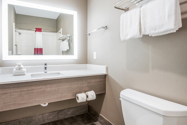 A modern bathroom with a white sink, mirror, and toilet. - Red Roof Inn Baytown (Baytown)