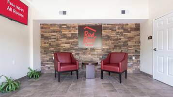 A reception area with a stone wall, two red chairs, a small table, and a sign indicating free Wi-Fi.