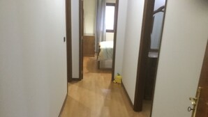 Un estrecho pasillo con suelo de madera y paredes blancas.
