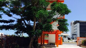 Ein Gebäude mit roter und weißer Fassade, umgeben von Grün und blauem Himmel.