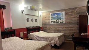 Ein Hotelzimmer mit zwei Betten, einer Holzwand, einem Fenster mit Blick auf den Strand und einem Schreibtisch mit Stuhl.
