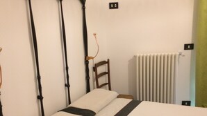 Ein Bett mit Holz Kopfteil, einer weißen Matratze und einer schwarzen Tagesdecke.