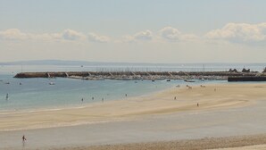 Ein Strand mit Booten, einer Mole und einem sandigen Ufer.