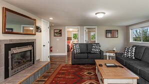 Ein Wohnzimmer mit Kamin, zwei Sofas, einem Couchtisch und einem gemusterten Teppich.