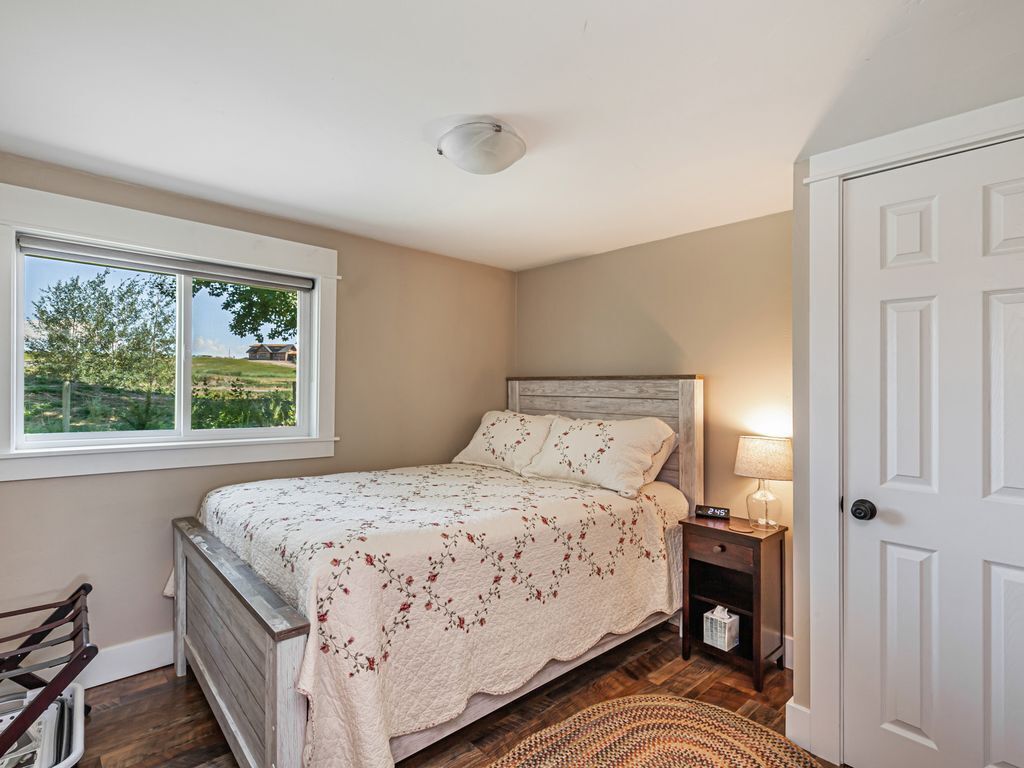 A bedroom with a bed, a nightstand, a lamp, a window, and a door.