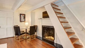 Une pièce avec une cheminée, une table à manger avec des chaises et un escalier.