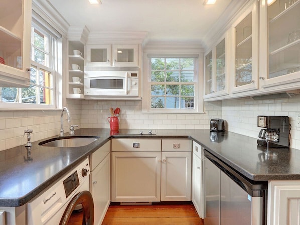 A kitchen with white cabinets, a microwave, a dishwasher, and a coffee maker. - Heated Pool Access | 5*Clean | Flex Cancelation (Savannah)