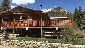 A wooden cabin with a balcony, stone wall, and a sign indicating no parking. - Wonderful, family friendly 5 Bedroom Cabin in Downtown Red River! (Red River)