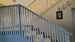 Una scala con ringhiera blu, pareti color beige e opere d'arte incorniciate.