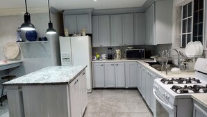 Una cucina moderna con mobili grigi, un'isola centrale, un piano cottura e un forno a microonde.