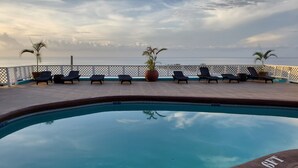 Una piscina con lettini e vista sull'oceano.