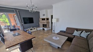Ein modernes Wohnzimmer mit einem Holzesstisch, einem braunen Sofa und einem an der Wand befestigten Fernseher.