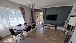 Ein modernes Wohnzimmer mit Essbereich, einem Flachbildfernseher und einem Kamin.