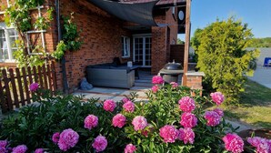 Ein Backsteinhaus mit Ziegeldach, Holzpforte und Garten mit rosa Blüten.