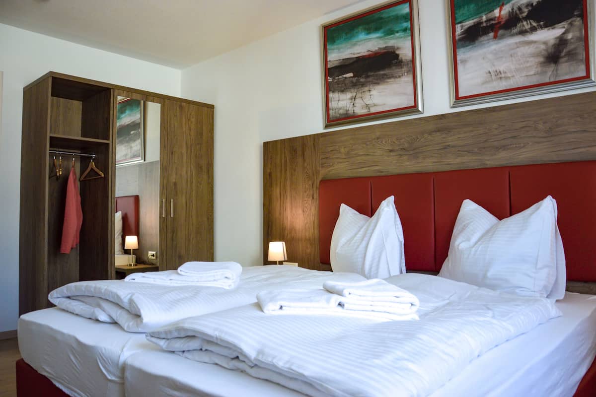A hotel room with a large bed, a wardrobe, and two bedside tables.
