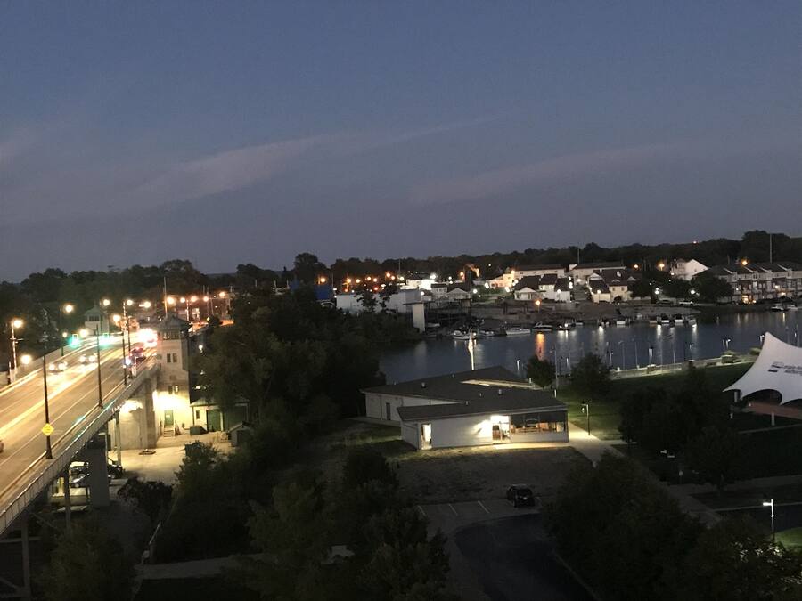 A nighttime view of a riverside town with illuminated streets and buildings.