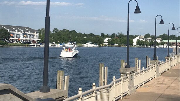 Eine Uferpromenade mit einer Reihe von Laternen und einem weißen Boot auf dem Wasser.