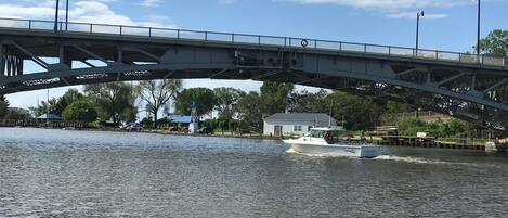 Un puente sobre un río con una embarcación llamada 'Ethan's Boat' pasando debajo.
