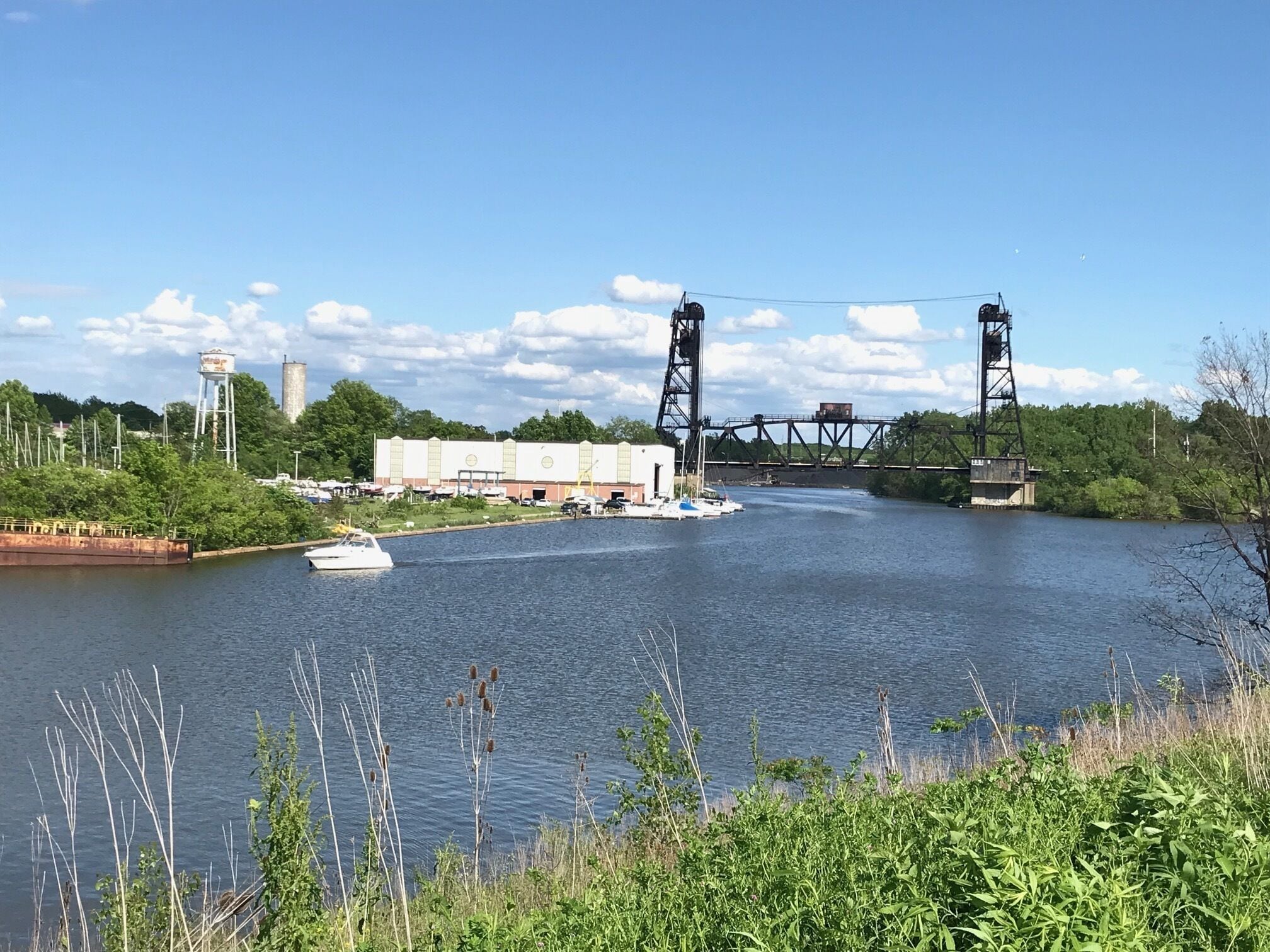 Un río con un puente, una embarcación y edificios industriales.