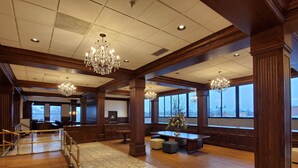 Eine geräumige Lobby mit hohen Decken, großen Kronleuchtern, Holzvertäfelung und Blick ins Freie.
