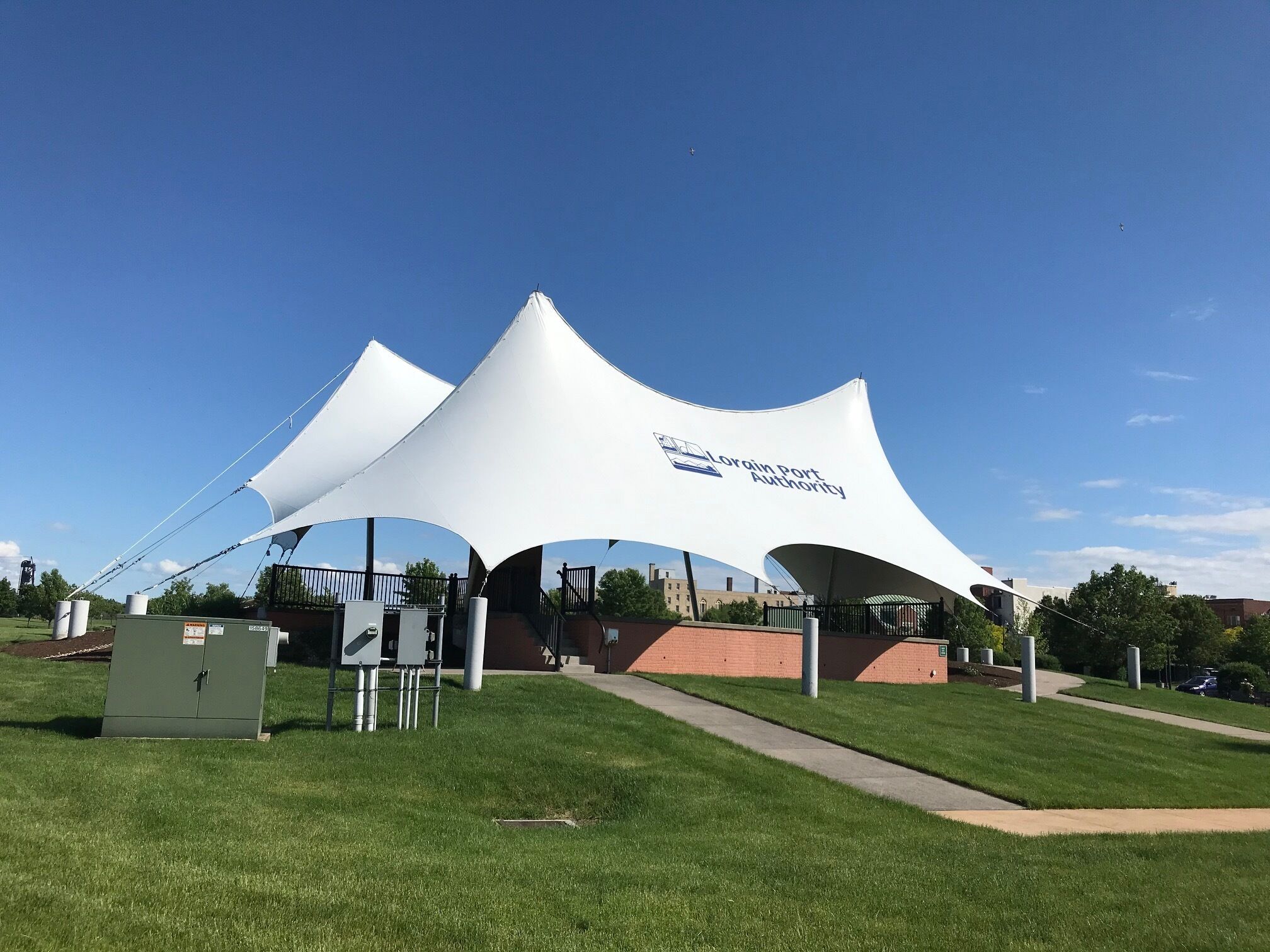 A white tent-like structure with the text "Lorin Port Authority" on it, set in a grassy area with a clear sky.