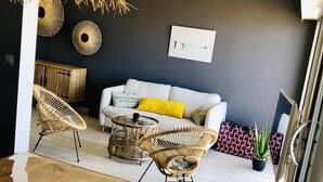 Una sala de estar moderna con un sofá blanco, sillones de mimbre, una mesa de centro de madera y un paraguas grande tejido.